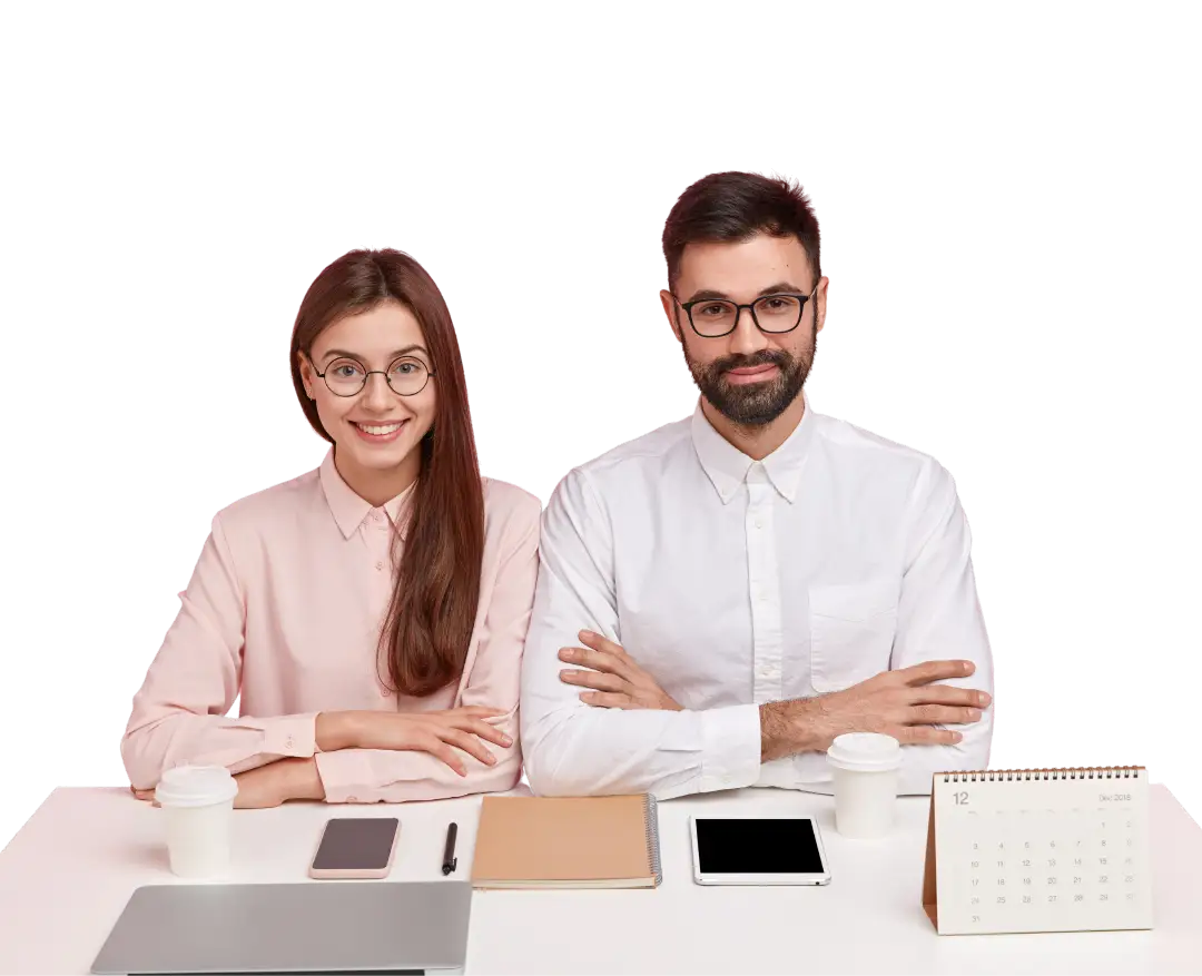 Un hombre y una mujer sentados en un escritorio con los brazos cruzados y mirando a la camara