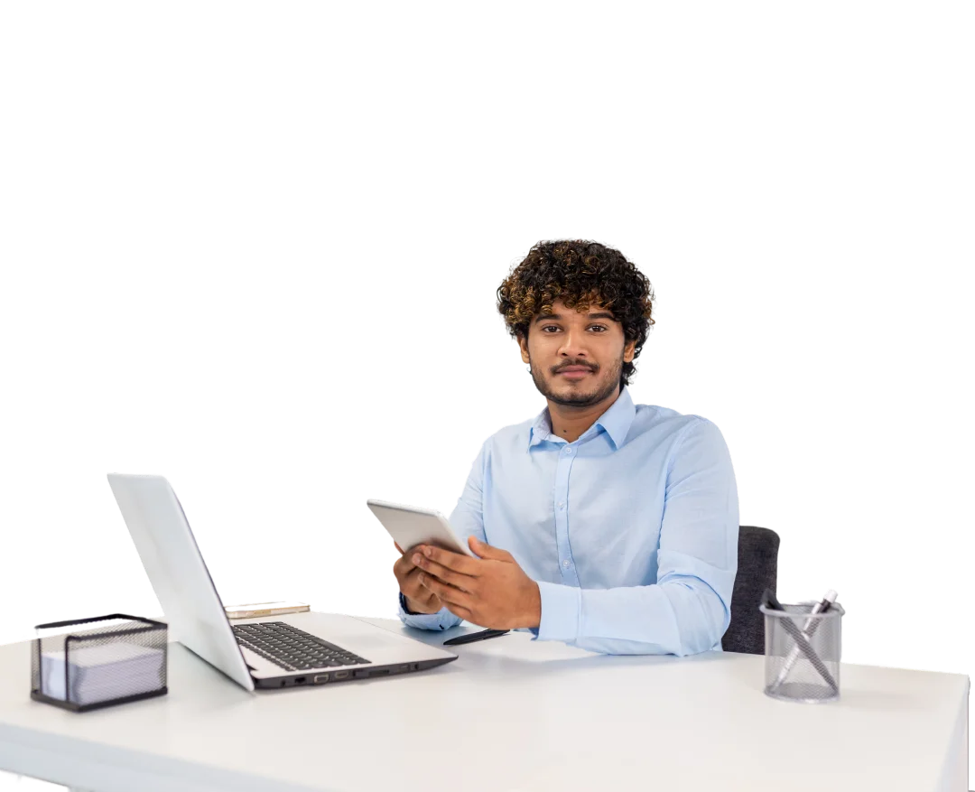 Un hombre trabajando en su escritorio con una laptop y una tablet.
